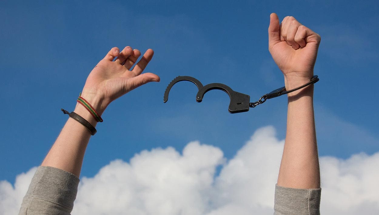 A person’s arms in the sky getting out of handcuffs