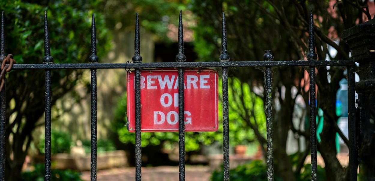 A sign saying “Beware of dog,” typically used to avoid litigation from a dog bite lawyer.