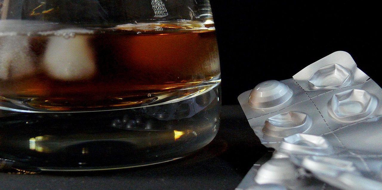 An alcoholic drink next to pills