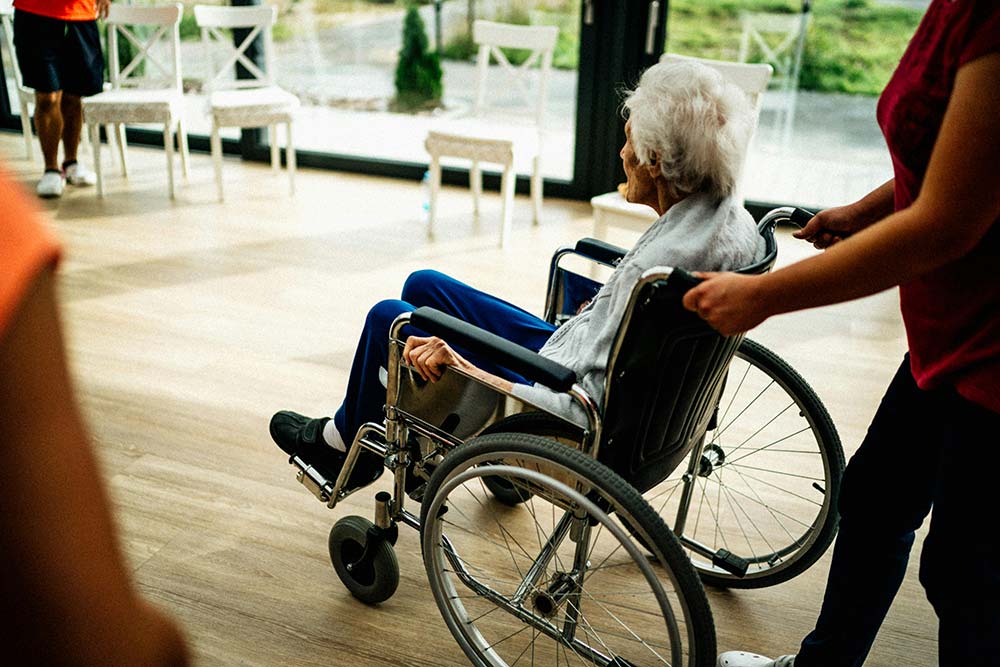 A person pushing a senior citizen in a wheelchair