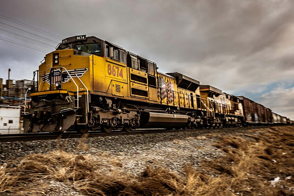 A yellow train traveling on railroad tracks