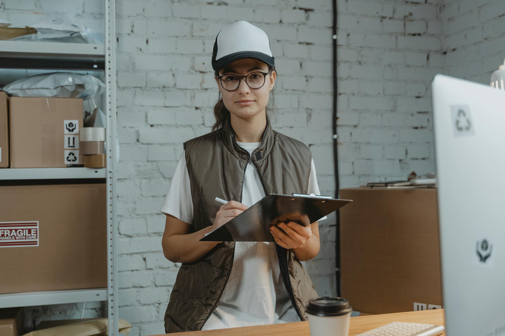 Fulfillment center workers reviewing paperwork at a warehouse desk, commonly referenced in Amazon fulfillment center workplace workers’ compensation FAQs