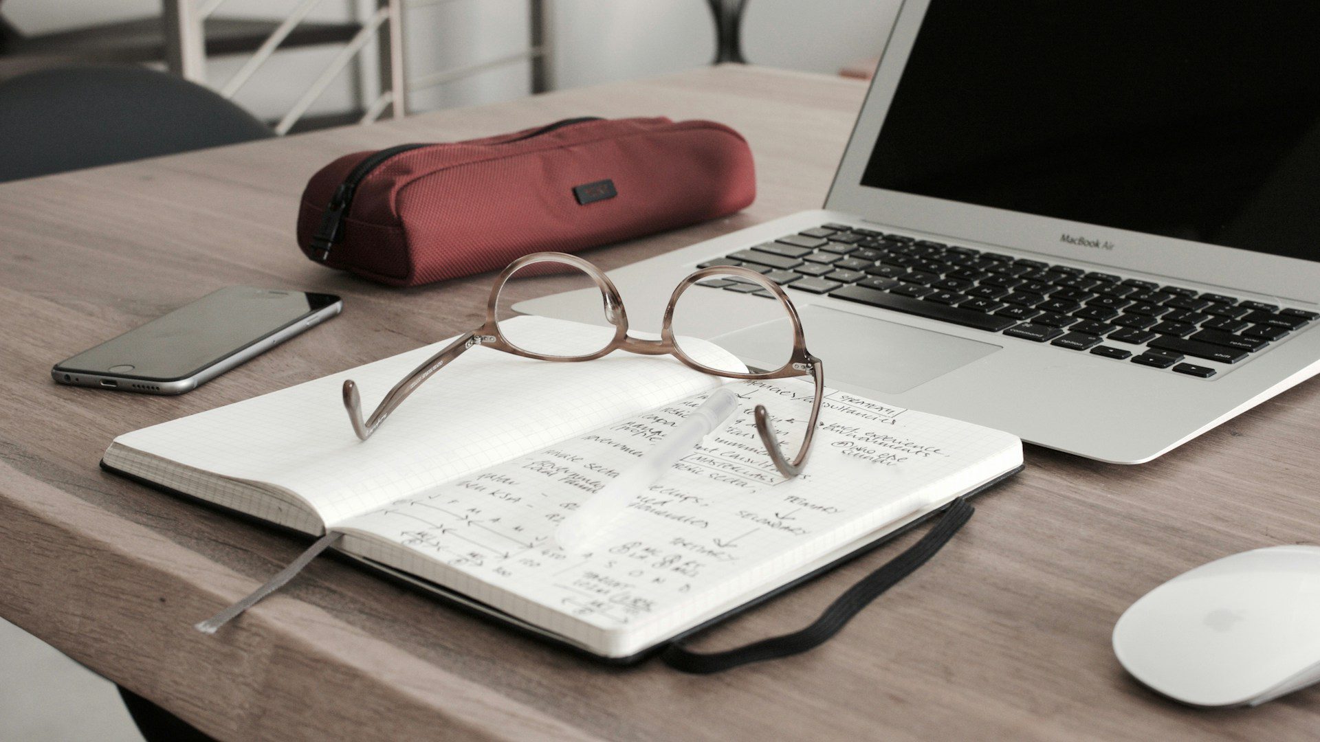 Glass and a notebook next to a laptop someone is using to access Boeing workers’ compensation FAQs