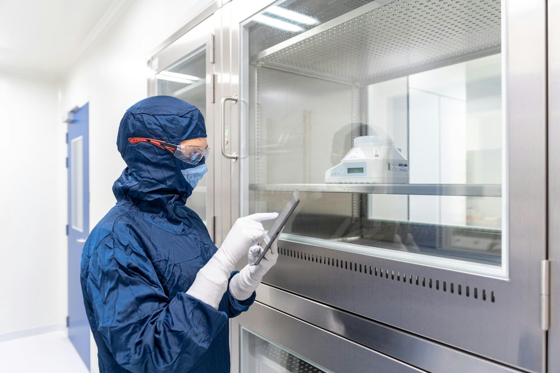 A person in blue lab gear using a device to access Nephron Pharmaceuticals Manufacturing workers' compensation FAQs
