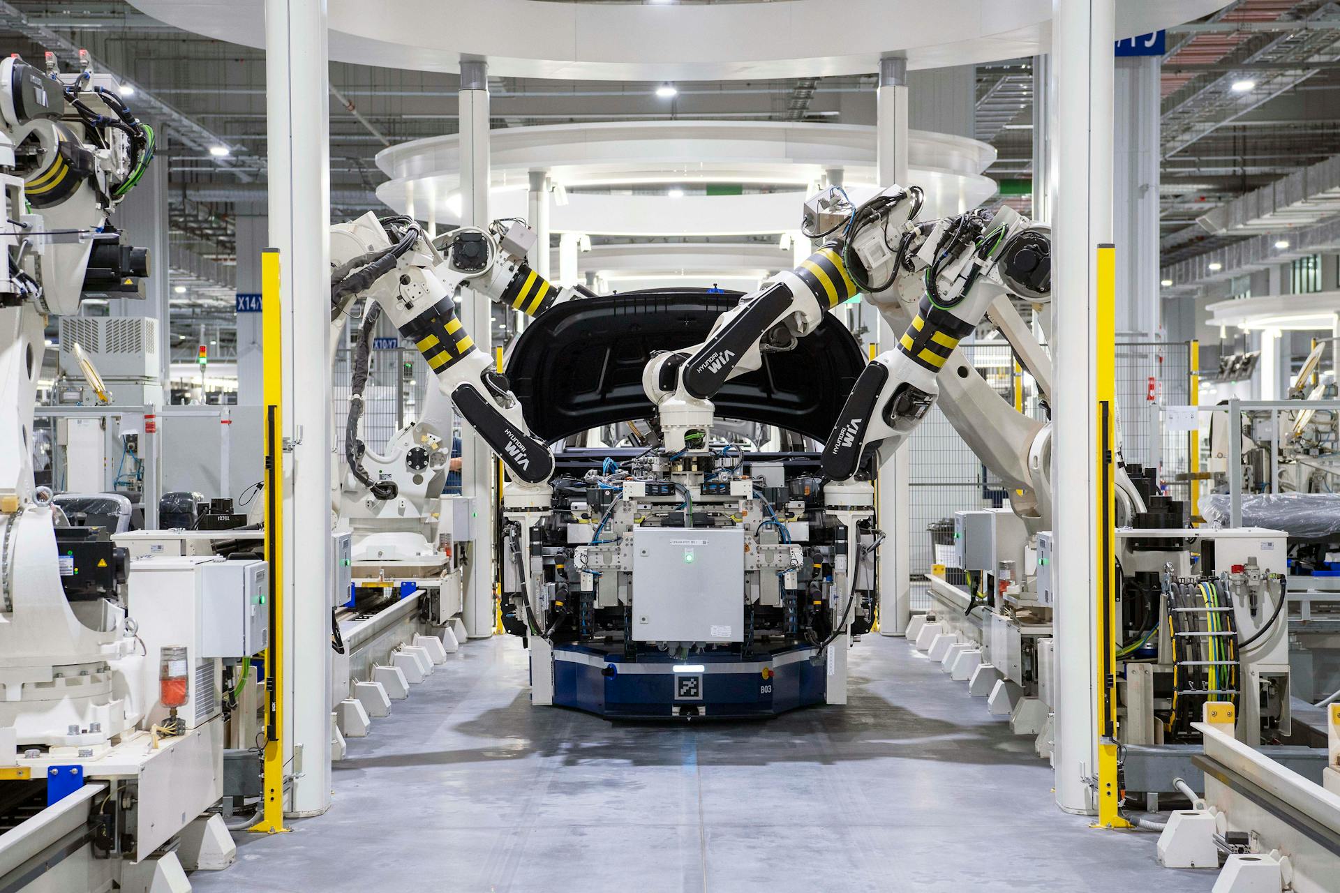 Robotic arms assembling a vehicle on a Volvo manufacturing line, commonly referenced in Volvo workers’ compensation FAQs about workplace injuries.