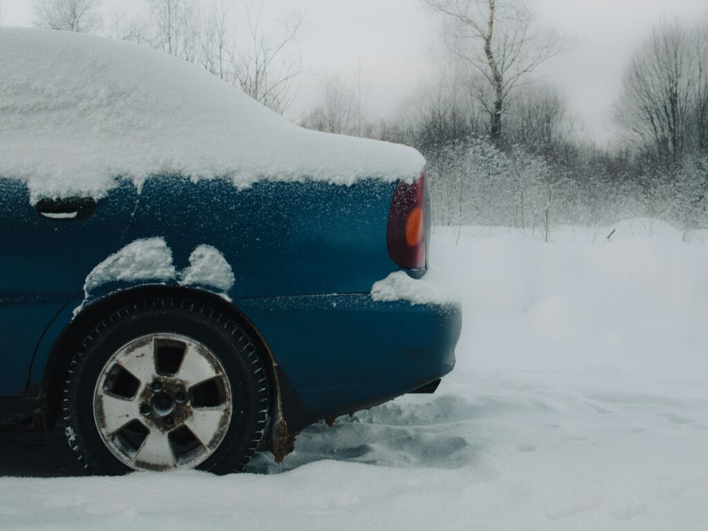 An image details a holiday road travel hazard as a blue car is stuck in the snow