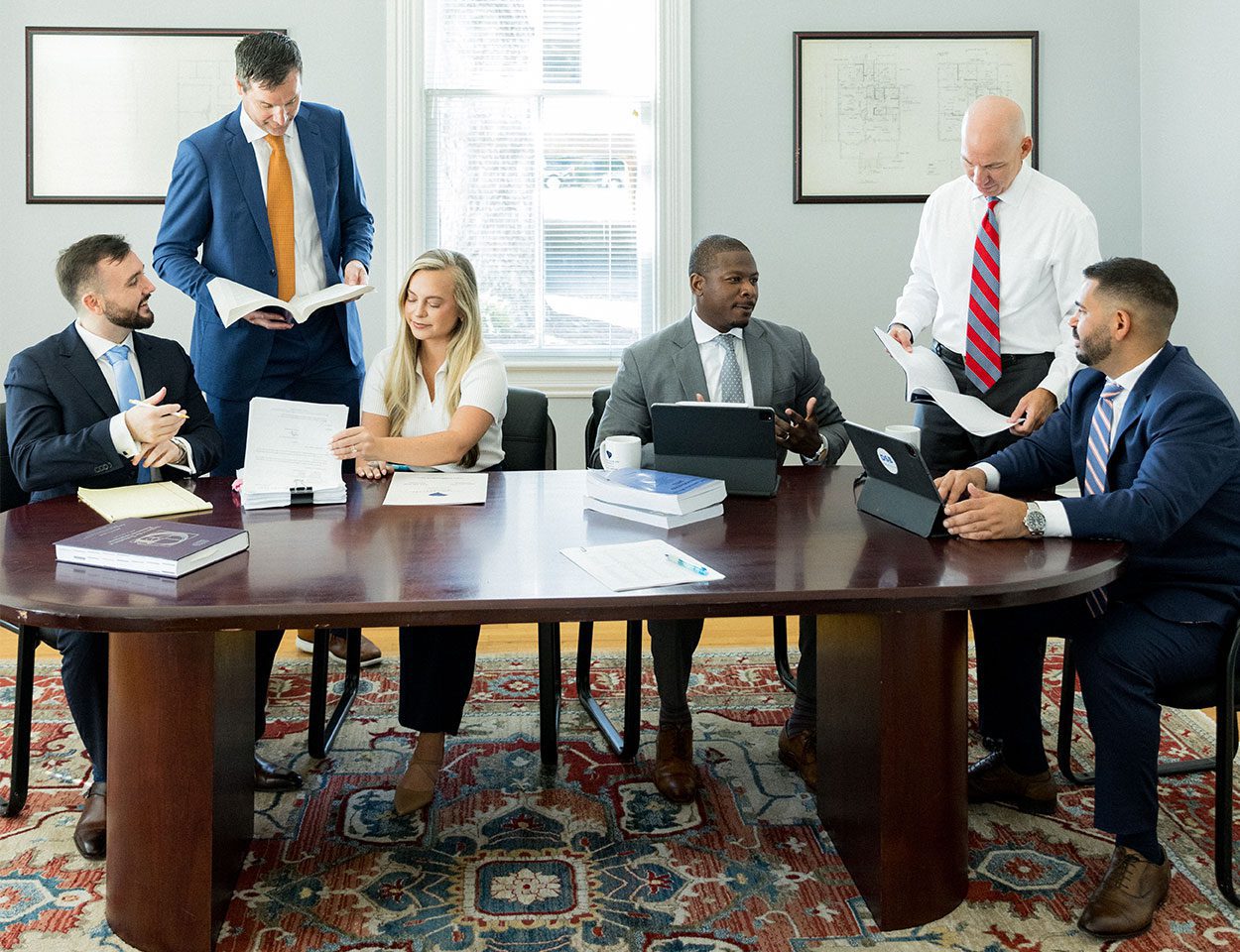 A group of Charleston car accident lawyers sitting and standing around a large table
