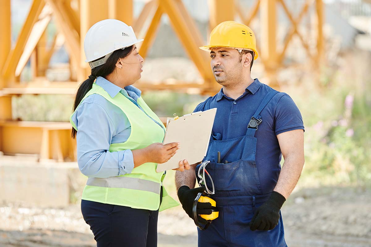 Two construction workers talking about contacting Charleston workers’ compensation lawyers