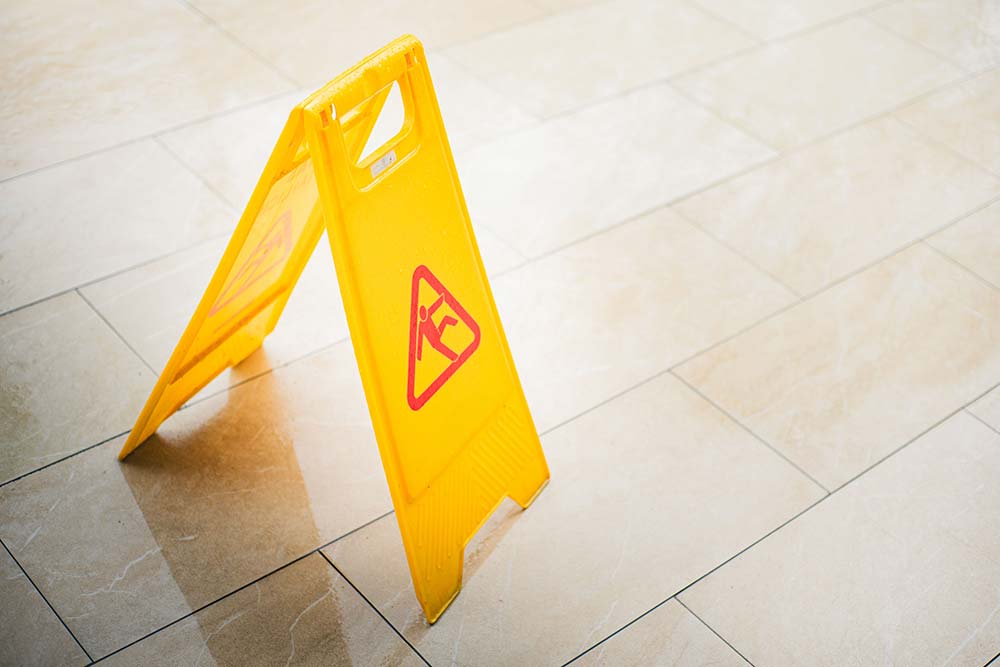 A wet floor caution sign on tile, a hazard involved in cases handled by Charleston premises liability attorneys